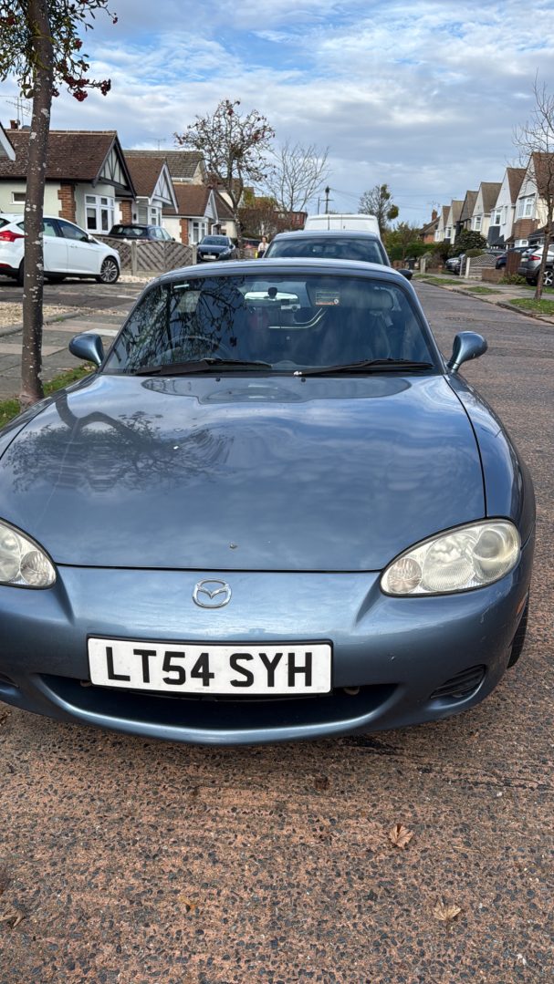 A blue sports car parked on a residential street.